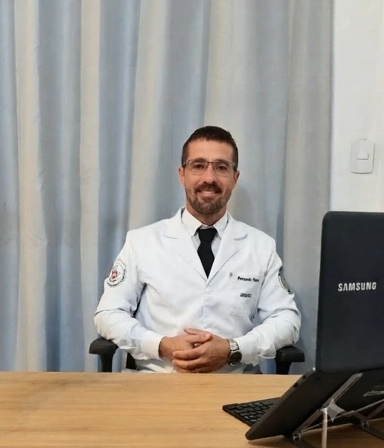 Dr. Fernando Guerra sorrindo, sentado à mesa do consultório